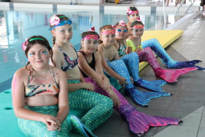 Jeunes nageuses inscrites au cours de nage sirène de la piscine Roudière assises le long du bassin - Agrandir l'image 1 sur 6, fenêtre modale