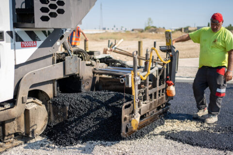 Chantier des enrobés de la zone d'cativité des hauts banquets. Un ouvrier verse le goudron de la toupie du camion au sol