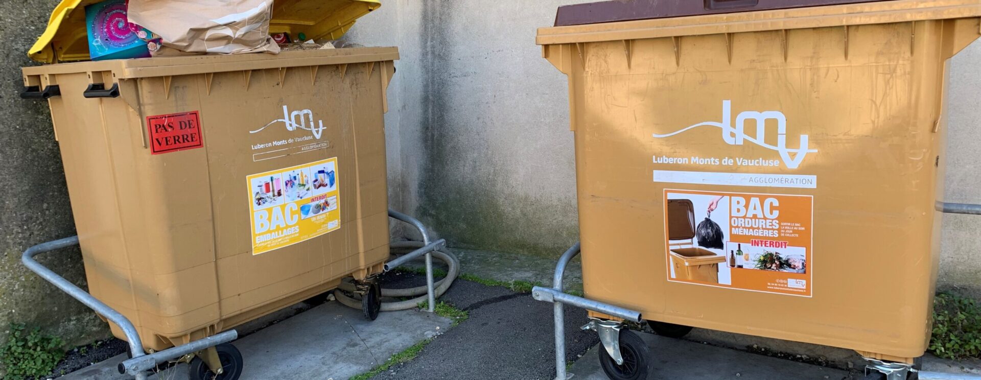 Bacs de collecte des déchets jaune (pour les emballages) et marron (pour les ordures ménagères) roulant avec les consignes de tri apposées par un stickers