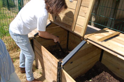 Homme en train de mélanger du compost dans le composteur à l'aide d'un outil - Agrandir l'image, fenêtre modale