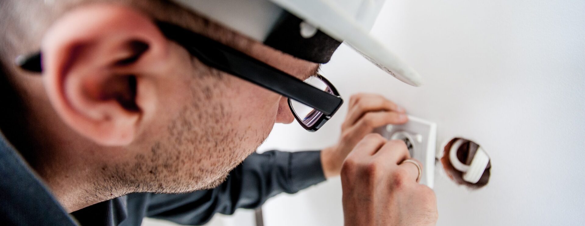 Électricien casqué en train de changer une prise de courant