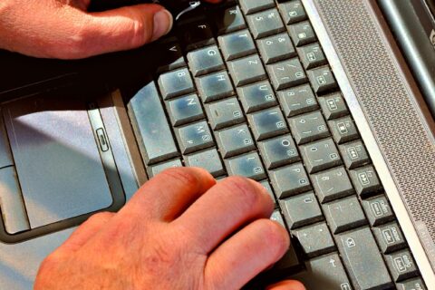 Gros plan de mains tapant sur un clavier d'ordinateur