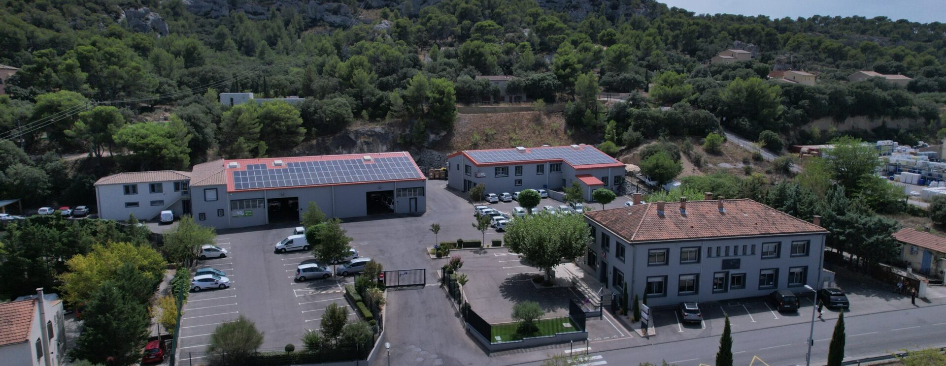 Vue drone du siège LMV avec ses trois bâtiments dont deux sont équipés de panneaux solaires et son parking