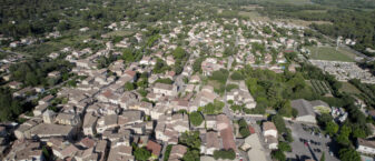 Mérindol vue d'un drone. Au premier plan : le village, l'école, la médiathèque. A droite : le stade. au fond : l'Espace Naturel Sensible La Garrigue