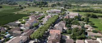 Oppède vue d'un drone. Au premier plan : la rue des Poulivets qui dessert la mairie, l'école, la médiathèque. Au 2e plan : la plaine. Au fond : Le Luberon