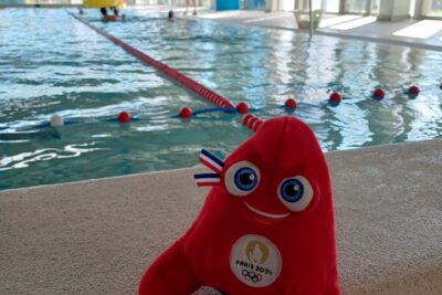 Mascotte officielle des JO Paris 2024 posée devant le grand bassin de la piscine Alphonse Roudière - Agrandir l'image 2 sur 6, fenêtre modale