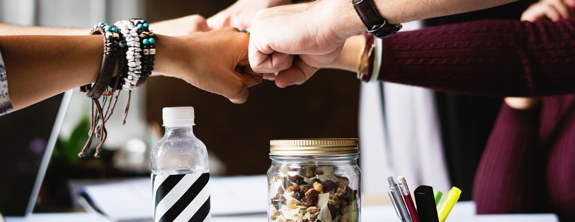 Photo sur laquelle on voit en gros plan 5 personnes se "checker", poing fermé, à l'image d'une équipe unie