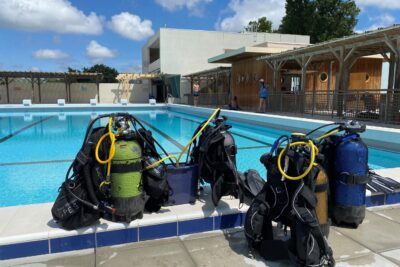 Photo de matériel de plongée (bouteilles et gilet) posé sur le bord du grand bassin du centre aquatique de plein air de Cavaillon - Agrandir l'image 1 sur 1, fenêtre modale