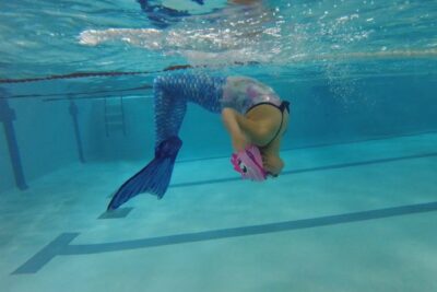 Jeune nageuse du cours de nage sirène, vêtue d'une queue de sirène, en train de faire une figure en apnée sous l'eau - Agrandir l'image 3 sur 6, fenêtre modale