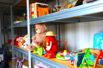 Jouets, doudous et objets du quotidien disposés sur une étagère qui se trouve dans un conteneur. - Agrandir l'image, fenêtre modale