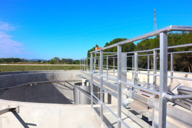 Station d'épuration où l'on voit une grande cuve vide avec un pont sur lequel on peut passer au dessus de cette cuve